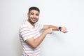 Good result and ontime. Happy handsome bearded young man in striped t-shirt standing, showing his smart watch and looking at Royalty Free Stock Photo