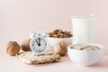 Good sleep. Alarm clock on the background of products for good falling asleep - milk, walnuts, oatmeal crispbread on a pink