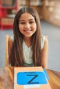 She is a good student. Portrait of a cheerful little girl doing her schoolwork while being seated in a classroom inside Royalty Free Stock Photo