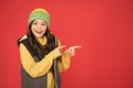 Good stuff that. Happy girl pointing index fingers red background. Small child in winter style pointing at something