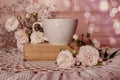 Good summer morning wishes: a cup of tea stands on a book, a bouquet of delicate roses, a lace napkin, bokeh, space for text Royalty Free Stock Photo