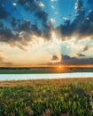 sunset in low clouds over river and green meadow Royalty Free Stock Photo