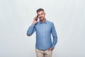 Good talk. Handsome bearded man in casual wear talking on the phone and smiling while standing against grey background Royalty Free Stock Photo
