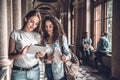 We are good team! Two beautiful students in the university looking at the tablet,reading and preparing for exams