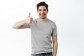 Good, well done. Smiling handsome man shows thumbs up with satisfied face expression, standing over white background