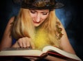 Good witch in the hat reads magic spells in the book on the fog background Royalty Free Stock Photo