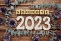 Goodbye 2023 alphabet letters with flower decorate on wooden background