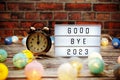 Goodbye 2023 text in light box with alarm clock and LED cotton balls decoration