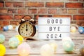 Goodbye 2024 text in light box with alarm clock and LED cotton balls decoration