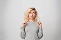 Goodlooking blonde female with pierced nose, wears gray sweater looks in amazement as indicates at something upwards.