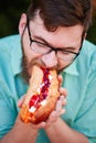 Goodly boy with a glasess tasting delicious food in the park. Nature background.