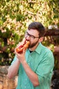 Goodly boy with a glasess tasting delicious food in the park. Nature background.