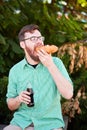 Goodly boy with a glasess tasting delicious food in the park. Nature background.