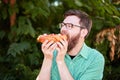 Goodly boy with a glasess tasting delicious food in the park. Nature background.