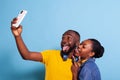 Goofy couple sticking tongue out and taking pictures on smartphone Royalty Free Stock Photo