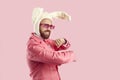 Happy man in funny Easter bunny ears and party glasses dancing on pink background Royalty Free Stock Photo