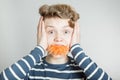 Goofy young boy with a mouthful of carrot