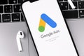 Google Ads logo mobile app on the screen smartphone iPhone with AirPods Royalty Free Stock Photo