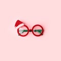 Google glasses Santa`s Christmas on pastel pink background. Masquerade festive party new year funny sunglasses, trendy minimal