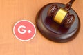Google plus paper logo lies with wooden judge gavel. Entertainment lawsuit concept