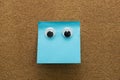 Googly eyes on clean blue  sticky note on cork board concept using sticky notes Royalty Free Stock Photo