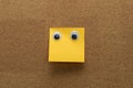 Googly eyes on clean orange sticky note on cork board concept using sticky notes Royalty Free Stock Photo
