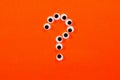 Googly eyes. Some middle size crazy toy eyes on orange background. In the shape of question mark