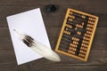 A goose feather lies on a pile of white sheets of paper. Old accounts and a retro inkwell are located side by side on a wooden tab Royalty Free Stock Photo