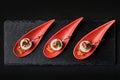 Goose liver pate, foie gras, served on black stone in Japanese red spoons. Paste served with jam and nuts. Fusion food