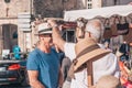 Gordes, Provence-Alpes-Cote d`Azur, France, September 25, 2018: Male tourists measure and bargain for a hat