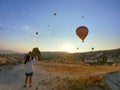Goreme, TURKEY - 2019: lady taking pictures of hot air balloons in cappadocia