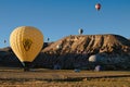 Balloons festival in Cappadocia. Big yellow hot air balloon with tourists landing on the trailer.