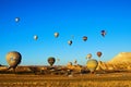 Hot air balloons festival in Cappadocia. Scenic view of landing balloons on the valley after morning flight.