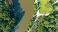 A gorgeous aerial shot of a silky green lake in the park surrounded by lush green grass and lush green and autumn colored trees