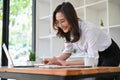 Gorgeous Asian businesswoman leaning working on her table, using calculator Royalty Free Stock Photo