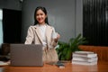 Gorgeous Asian businesswoman standing at her desk, holding a coffee cup Royalty Free Stock Photo