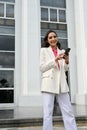 Gorgeous Asian businesswoman standing outside of the building and using he smartphone Royalty Free Stock Photo