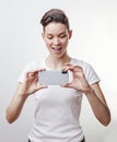 Gorgeous Asian teenage girl smile and take a photo using front camera in her smartphone, isolated on white background Royalty Free Stock Photo