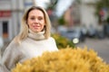 Blonde woman standing behind yellow flowers Royalty Free Stock Photo