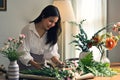 Gorgeous Asian woman enjoys arranging a vase with beautiful flowers at home Royalty Free Stock Photo