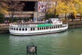 a gorgeous autumn landscape along the Chicago River with Chicago Cruise ferry boat, yellow autumn trees and people walking