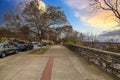 A gorgeous autumn landscape in the city along a sidewalk with autumn colored trees and parked cars along the street