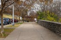 A gorgeous autumn landscape in the city along a sidewalk with autumn colored trees and parked cars along the street