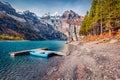 Gorgeous autumn scene of unique Oeschinensee Lake with small fishing boat.
