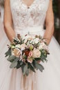 Gorgeous beautiful bride holding stylish wedding bouquet on back