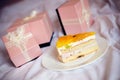 3 gorgeous beautiful luxury pink presents and delicious slice of cake on a plate on the white bed background