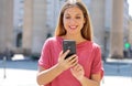 Gorgeous beautiful young woman with long hair chatting on smartphone in city street. Pretty girl having smart phone conversation Royalty Free Stock Photo