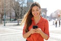 Gorgeous beautiful young woman with long hair messaging on the smart phone in city street. Pretty girl having smart phone Royalty Free Stock Photo
