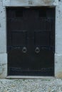 Gorgeous big old ancient black wooden door of stone building with knocker decorated with forgings carving. Architecture. Royalty Free Stock Photo