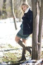 Gorgeous blond woman leaning against a tree with winter coat and high boots. Royalty Free Stock Photo